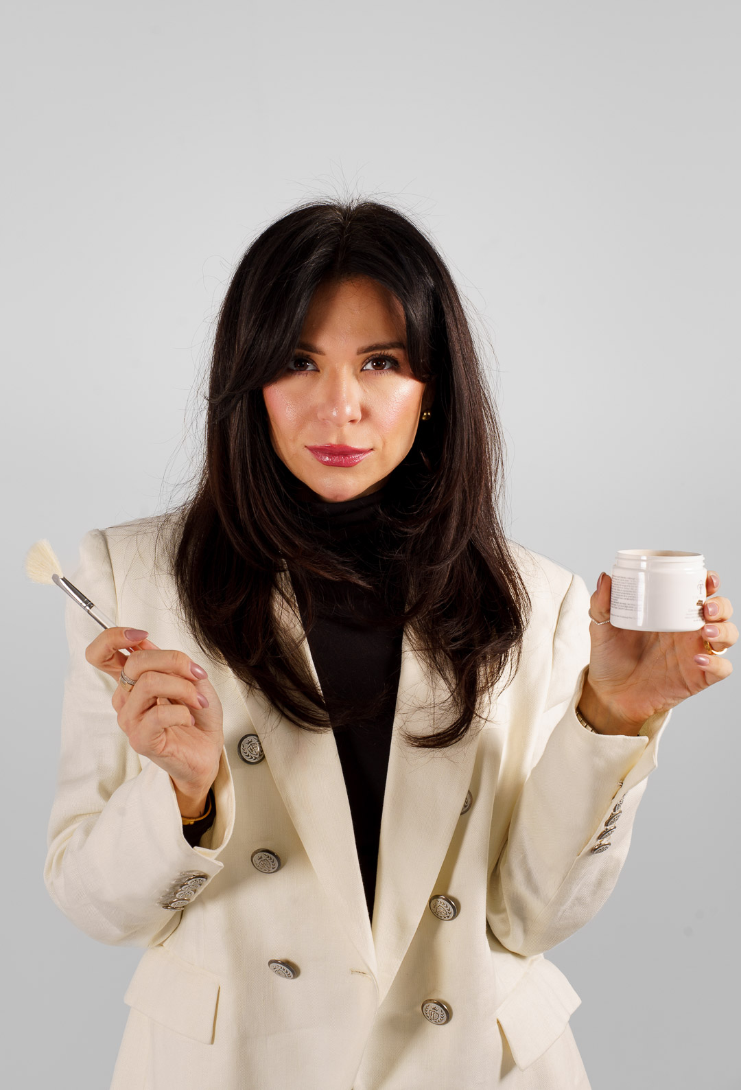 Esthetician holding skincare brush and cream jar used in chemical peel aftercare routine