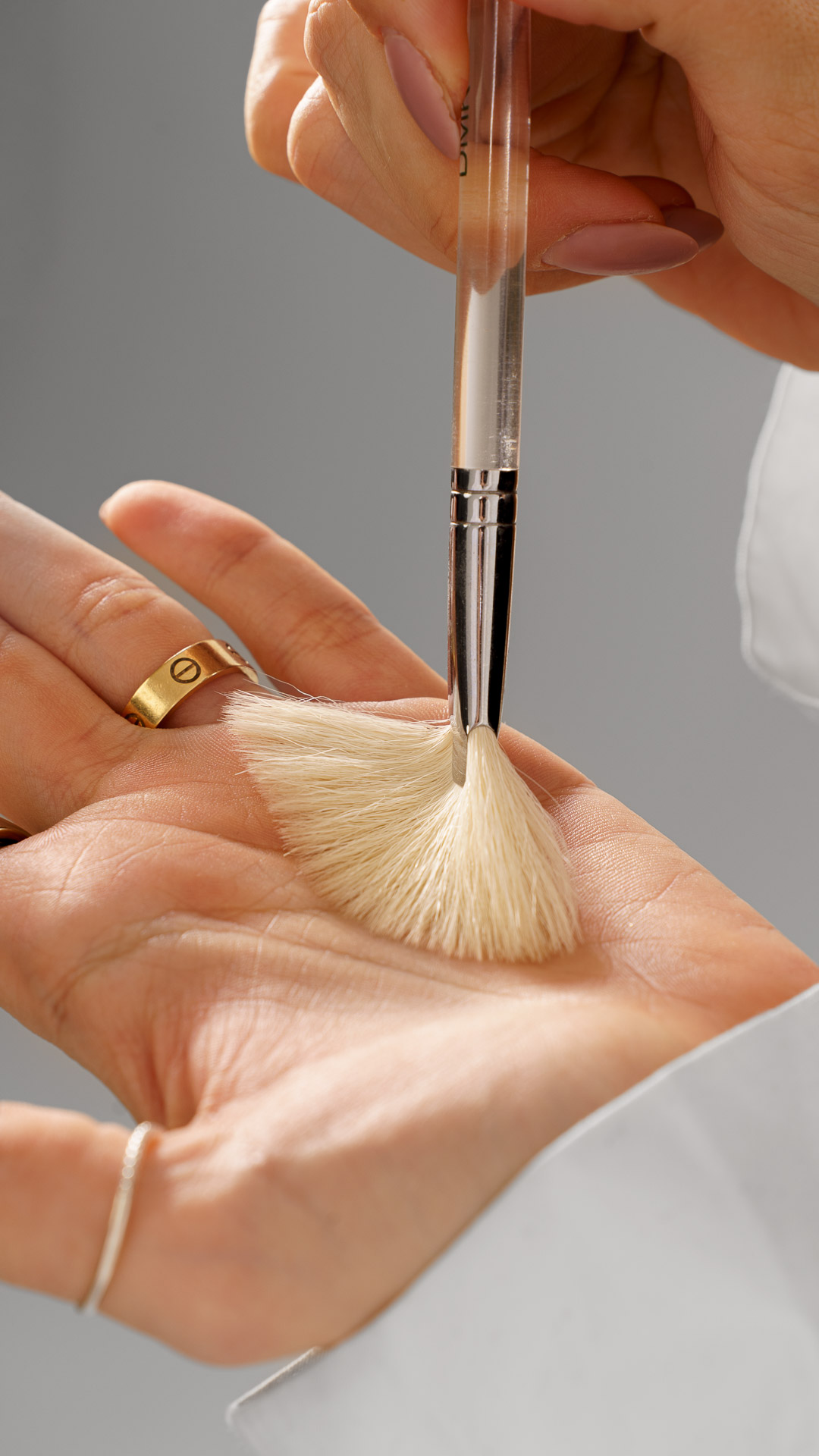 Close-up of hands applying a fan brush treatment to the palm during a facial